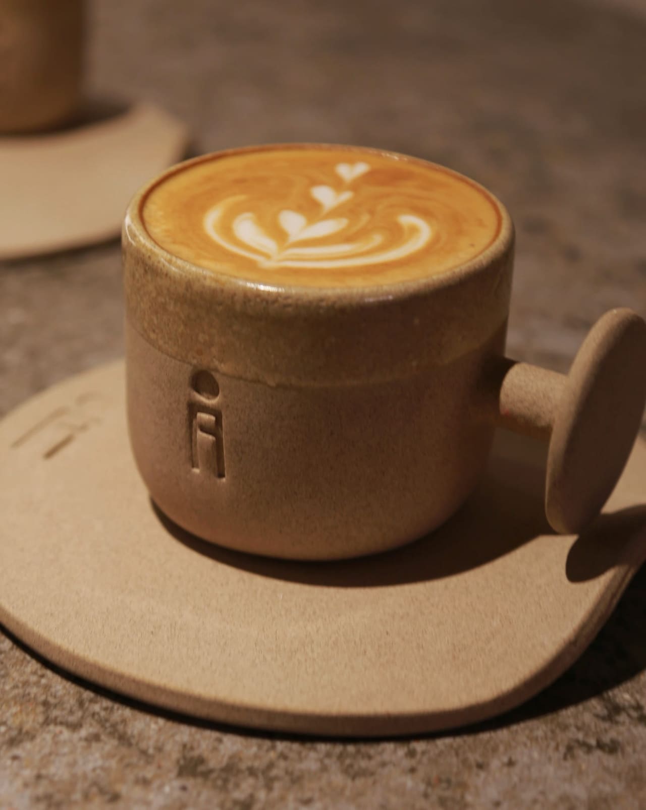 A latte with leaf-pattern art, served in an IF HUB branded cup